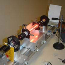 Photo shows a table-top contraption with a tube of glowing light and a dot of red light appearing on a screen at one end.