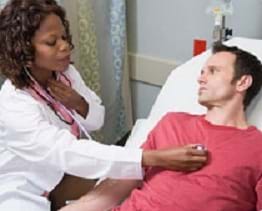 A female doctor listens to the heart of a male patient.
