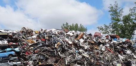 Photo shows a pile of assorted scrap metal in sunlight.
