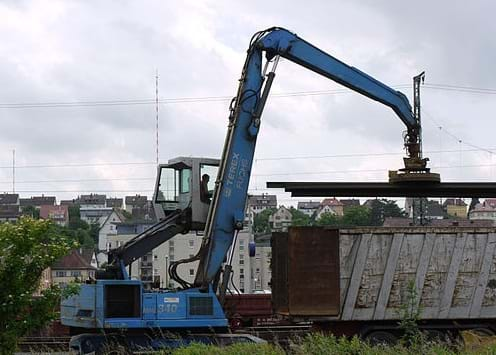 A photograph shows a crane-suspended electromagnet with the name "mule" holding steel beams over a truck bed.