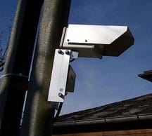 Photo shows a silver hooded metal box mounted on a street pole.