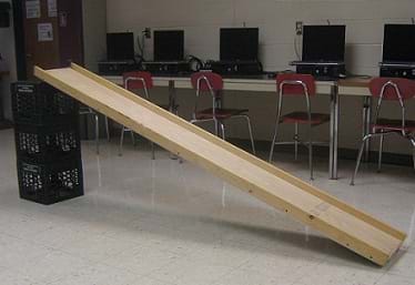 A photo shows a ramp made from an eight-foot wooden board with one end on the floor and the other end resting on the top of three stacked plastic milk crates.