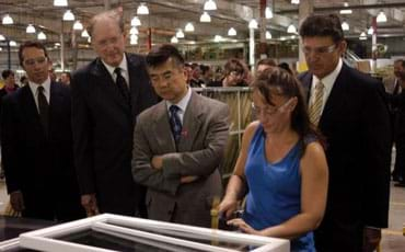 Photo shows a factory worker using tools to assemble a window frame.