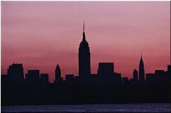 A distant skyline of entirely dark skyscrapers against a sunset pink sky.