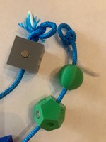 A photo of a blue cord with amino acid models on it and loops on both ends of the strand of amino acids. A photo of a blue cord with amino acid models on it and loops on both ends of the strand of amino acids.