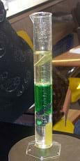 Photo shows a graduated cylinder containing different-colored layers and a few suspended solid items.